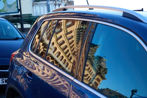 Scarborough Grand Hotel reflection This urban photograph captures the reflection of the Scarborough Grand Hotel in the windows of a blue car parked on a street in Scarborough, Yorkshire. The image was taken in the late afternoon during the spring season, and the Grand Hotel’s distinctive architecture is clearly visible as it appears distorted and mirrored in the car's glass. The clear blue sky and natural lighting enhance the details of the hotel's ornate facade, showcasing one of the iconic landmarks of Scarborough in Yorkshire from an artistic perspective.